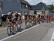 A group of cyclists riding single file.