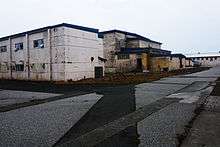 A series of large concrete buildings with peeling paint, clearly in a state of disrepair