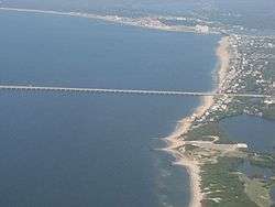 A sandy beach with a causeway that heads straight out into the water.