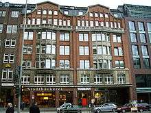 A multi-storey red brick building with a storefront.