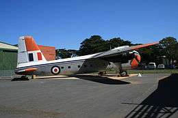 Twin-engined cargo plane painted white and grey with orange extremities, parked on tarmac