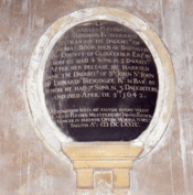 Round biographical plaque, with white letters on a black background