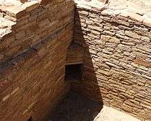 A color picture of a corner dorrway in a large sandstone wall