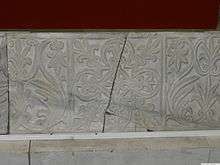 A stone block entirely covered by carvings of two alternating floral motifs, separated into square sections