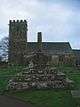 Part of the shaft of a stone cross and its mounting block on a square base of three steps