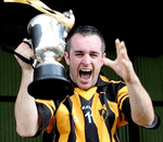 Man holding trophy wearing black and amber jersey