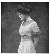 Black and white portrait of a white woman with dark hair. She wearing a light color dress and facing left.