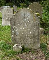 A granite headstone among other headstones