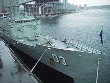 Photograph of a frigate's bow and the front of her superstructure. Two weapons systems can be seen on the forward deck.