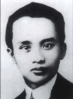 A young man, in a suit with a pale shirt and dark tie