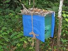 A teal coloured wooden box with blue coloured plastic cover.