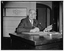 a middle-aged bald man sitting at a desk