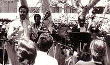 In this photo Herbert D. Smith talks to audience about the Bass Choir as Fred Tinsley (left) and John Heard (right) looks on.