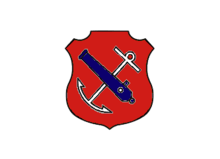 An insignia in the form of a red shield. On the shield are a white anchor crossed by a blue cannon barrel.