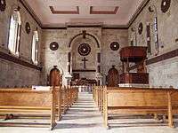 dark wood pews, altar and private royal pew carved with floral motifs and hung with red satin