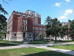 A U-shaped brick and stone building with a nine-story tower at its back on a clear summer day