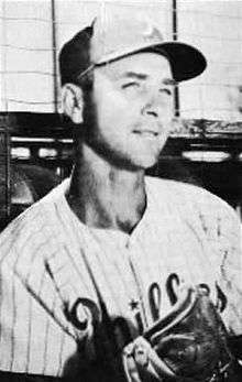 A black-and-white image of a man wearing a pinstriped baseball uniform and a dark-colored baseball cap