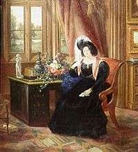 A color picture of an 1833 painting of Lady Tyrconnell sitting in a brown covered chair while in an 1830s dark blue full dress gown with puffy sleeves, reddish scarf and a dark feathered round hat. She is sitting in the carpeted Gothic style Drawing room next to a brown desk and light red drappered window.