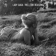 The singer lies in a field of grass in this black and white photograph.