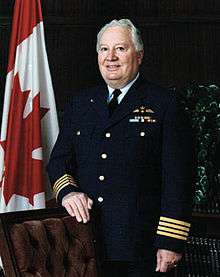 Canadian military officer standing in uniform beside Canadian flag