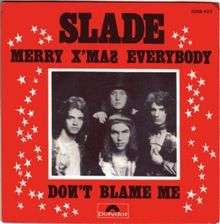 A monochrome photograph of Slade, with a white border, set almost centrally in a red square. The words "SLADE" dominate the cover, underneath which is written "MERRY X'MAS EVERYBODY". Underneath the photograph are the words "DONT BLAME ME". White stars border the left and right sides of the photograph.