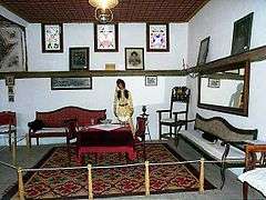 Living area with rug, table, two chairs and seating along the walls