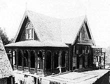 Two-storey wood house in the form of a cross, with decoratively carved ornamentation