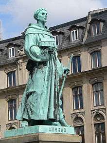 A young man in a monk's habit who holds the model of the church in his right hand and a walking stick in his left hand