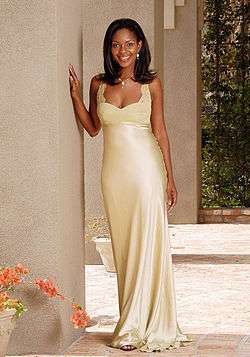 A tall black woman with long hair and earrings, wearing in a white gown