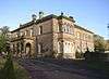 A stone house in two storeys, with an entrance portico and a two-storey bay window