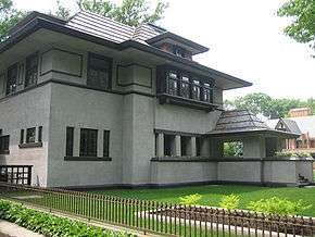 Recent exterior view of the house from the southeast corner.  The library windows are visible at left with the entrance porch at far right.  The living room planter with bedroom bay window are at center.  Deep eaves shade the house from the mid-day summer sun.