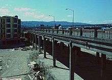 A car and two bicyclists going across a viaduct