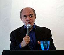 Photograph of a man, Pierre Assouline, seated with a microphone in his hand.