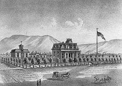 A black-and-white illustration showing the house on a large block surrounded by small trees, with a horse-drawn vehicle in front, large flag on a pole to the right, and mountains in the background