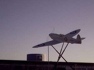 Spitfire replica, with auto-manufacturer logo in background