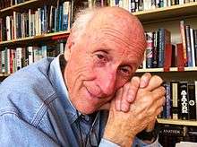 Man at home in front of a full bookcase