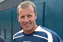 A man with brown hair is wearing a blue and white top.