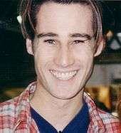 A colour photograph of a young man with a curtains hairstyle