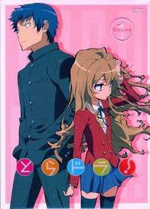 A DVD poster; near the top right hand corner is a circle with "scene 1" inscribed. In the foreground are a boy, looking to the left, and a girl, looking to the right, against a background of pink. Near the bottom, with each character in a respective circle, reads "Toradora!".