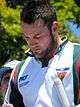 An Australian cricketer wearing a white shirt. A boy can be seen in the background.