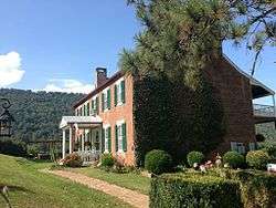 Side view of two-story brick house with green shutters